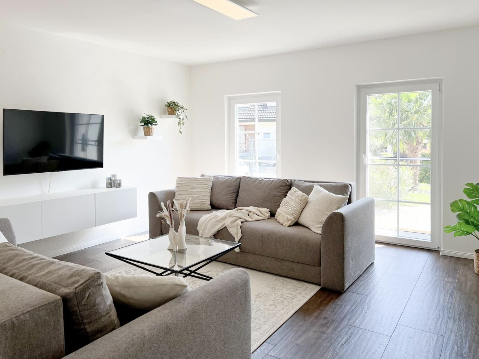 Moderne Ferienwohnung mit grauem Schlafsofa und Glas-Tisch