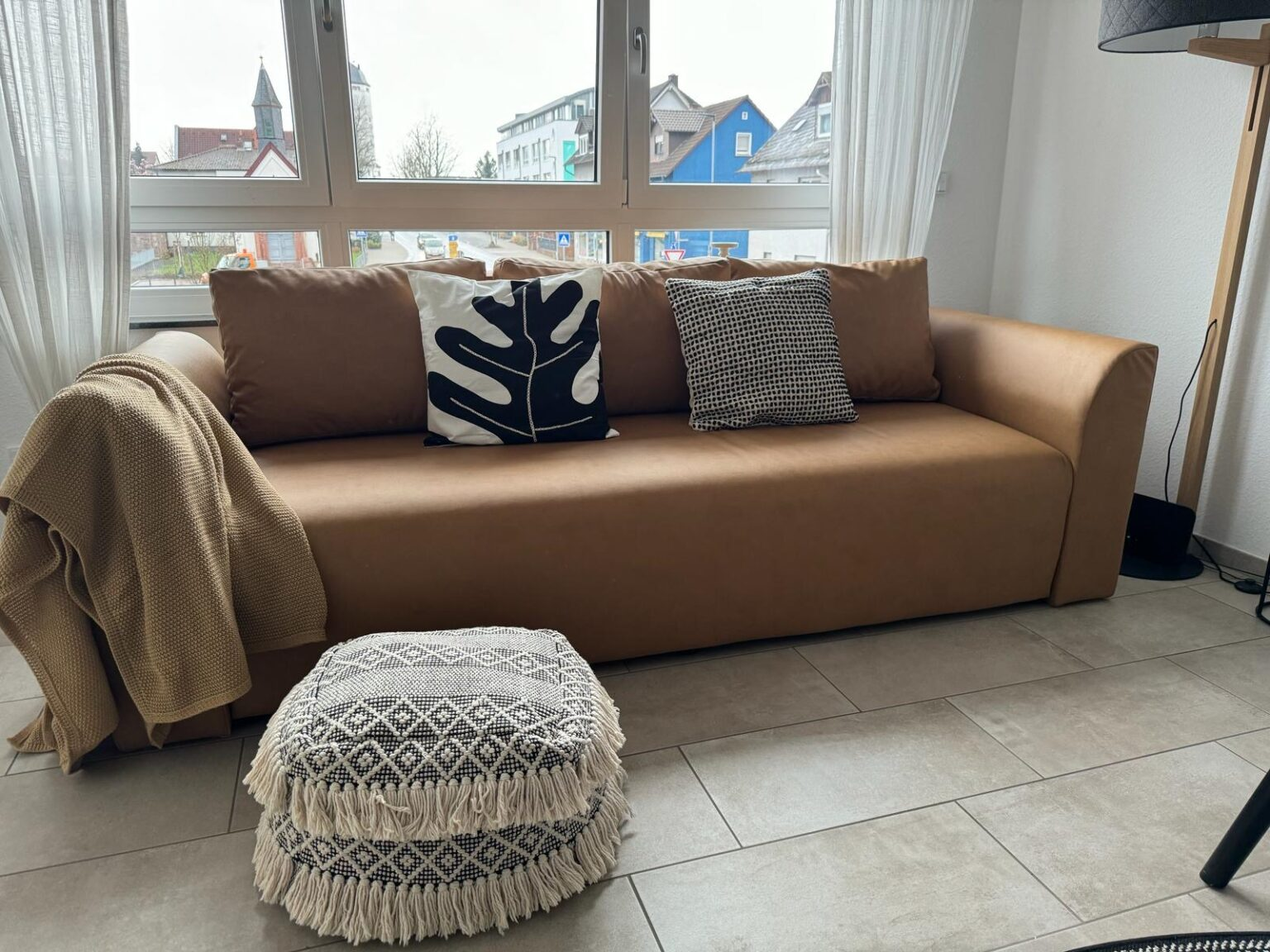Schlafsofa in Karamellbraun mit Pouf und Fensterblick