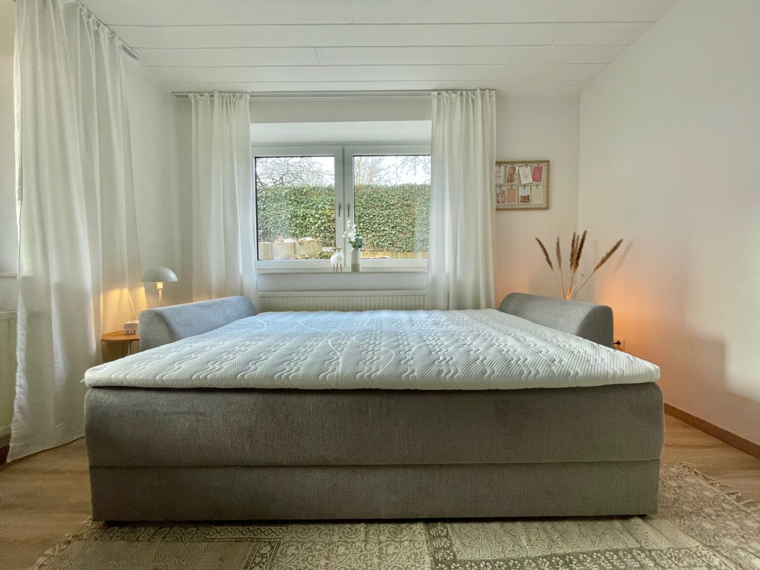 Schlafsofa als Bett aufgemacht mit Nachttisch und Lampe