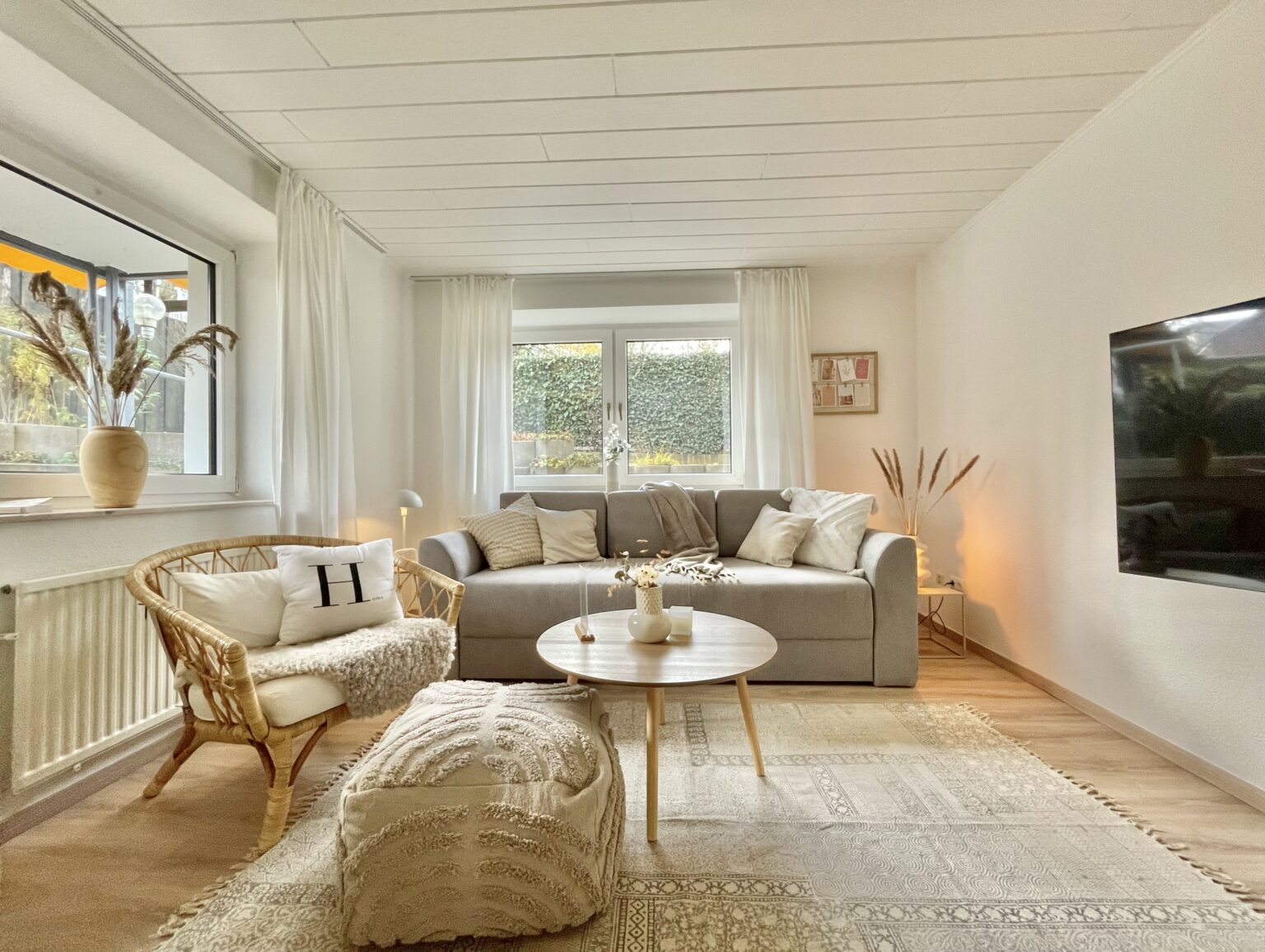 Schlafsofa in einer hellem Ferienwohnung mit hellgrauem Bezug und Deko